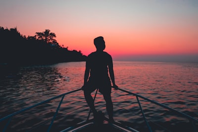 silhouette of a man sitting on fence of motorboat during golden hour chill google meet background