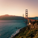 red metal bridge across teal body of water at daytime