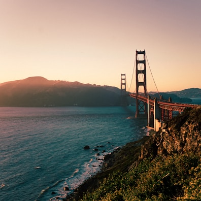 red metal bridge across teal body of water at daytime