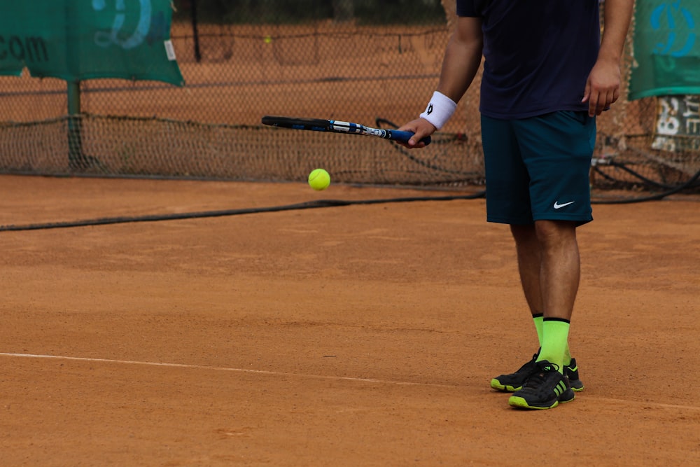 hombre en pantalones cortos Nike azules jugando al tenis