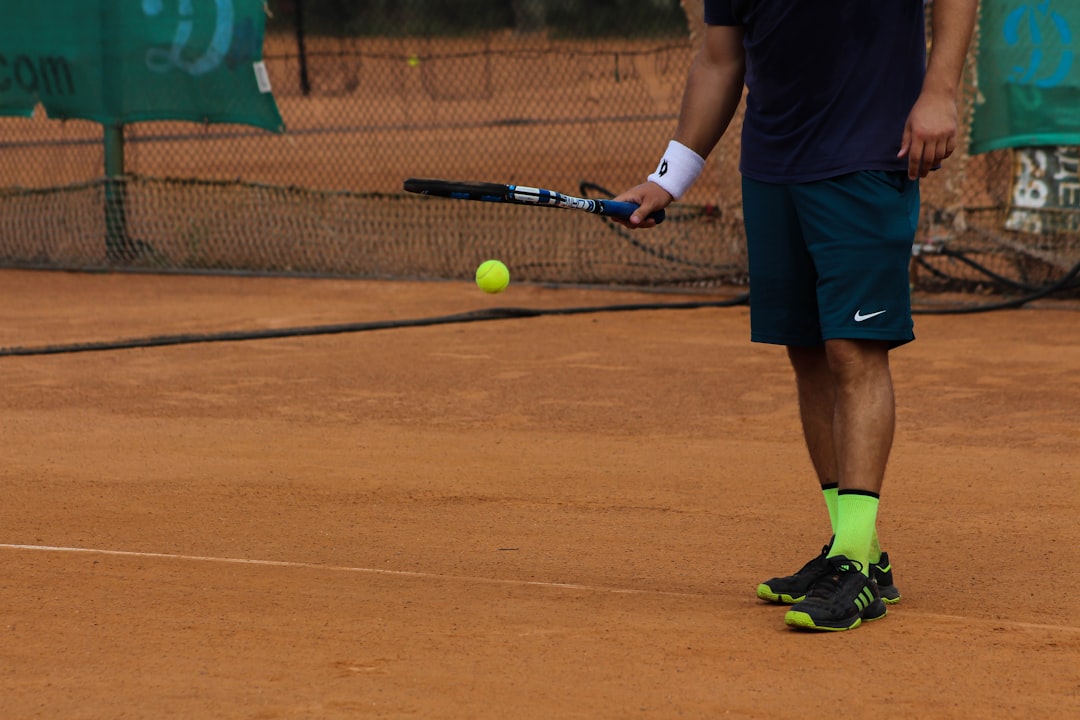 man in blue Nike shorts playing tennis,
