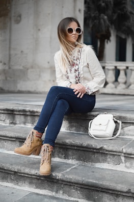 Woman sitting on urban steps, showcasing a pair of trendy Maguis Colletion boots with a casual outfit.