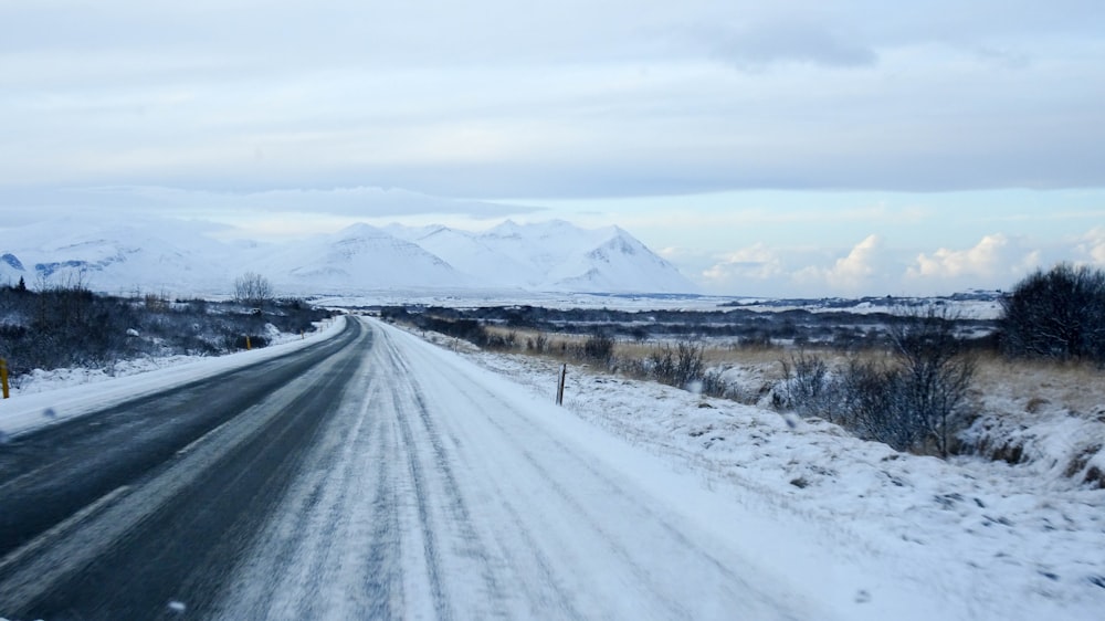 昼間の白い曇り空の下、雪に覆われたアスファルト道路