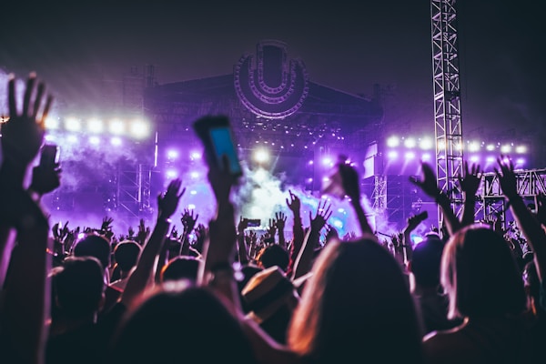 eine Gruppe von Menschen heben die Arme beim Feiern vor einer Festivalbühne