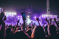 Público con los brazos en alto en un concierto con luces moradas