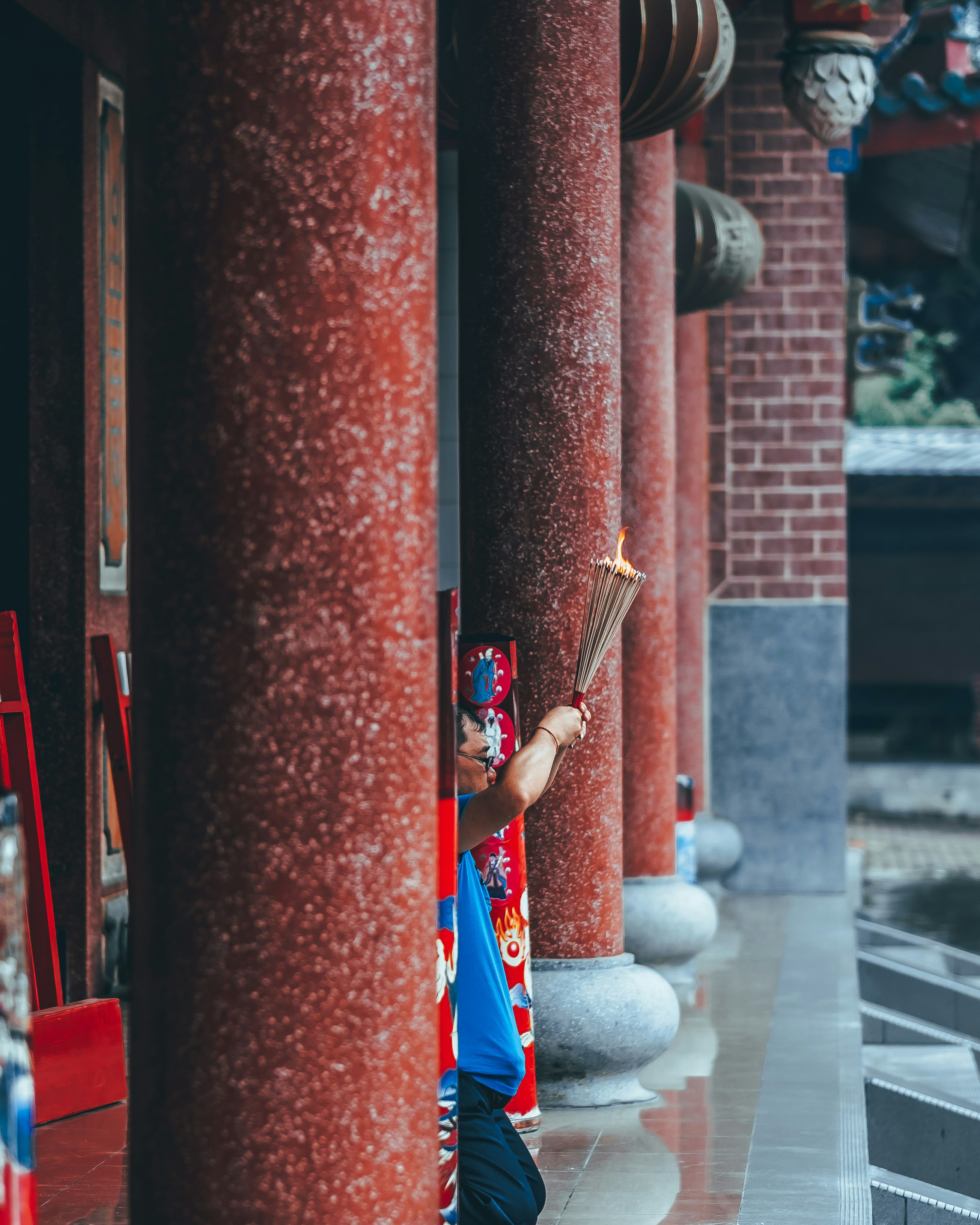 man kneeling while holding incense outdoors