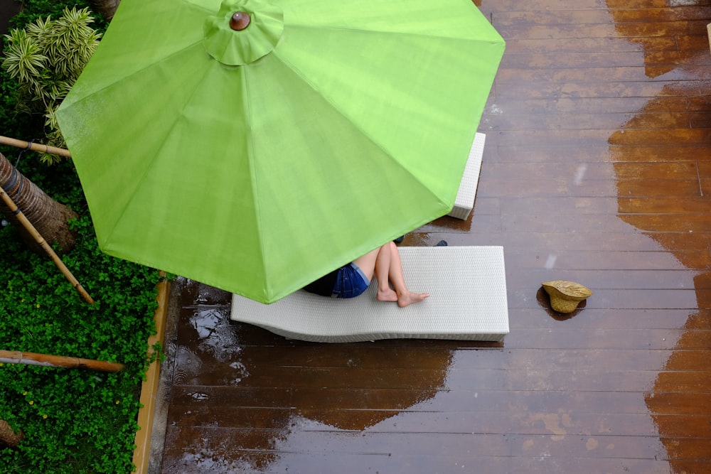 person lying on lounger under patio umbrella