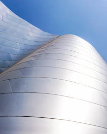 Close-up shot of sleek silver aluminum panels on a modern city skyscraper under clear blue sky.