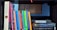 A bookshelf filled with various books, including a complete set of 'The Chronicles of Narnia' by C.S. Lewis, and titles like 'Visual Language for Designers' and 'The Hitchhiker's Guide to the Galaxy' by Douglas Adams. The books are neatly arranged, some placed vertically and others horizontally. The background features a wooden structure, adding a cozy and intellectual atmosphere.