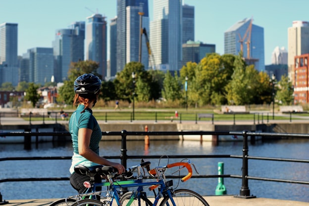 woman holding bicycle looking at the trees
