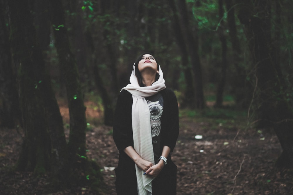 shallow focus photography of woman in forest looking upward
