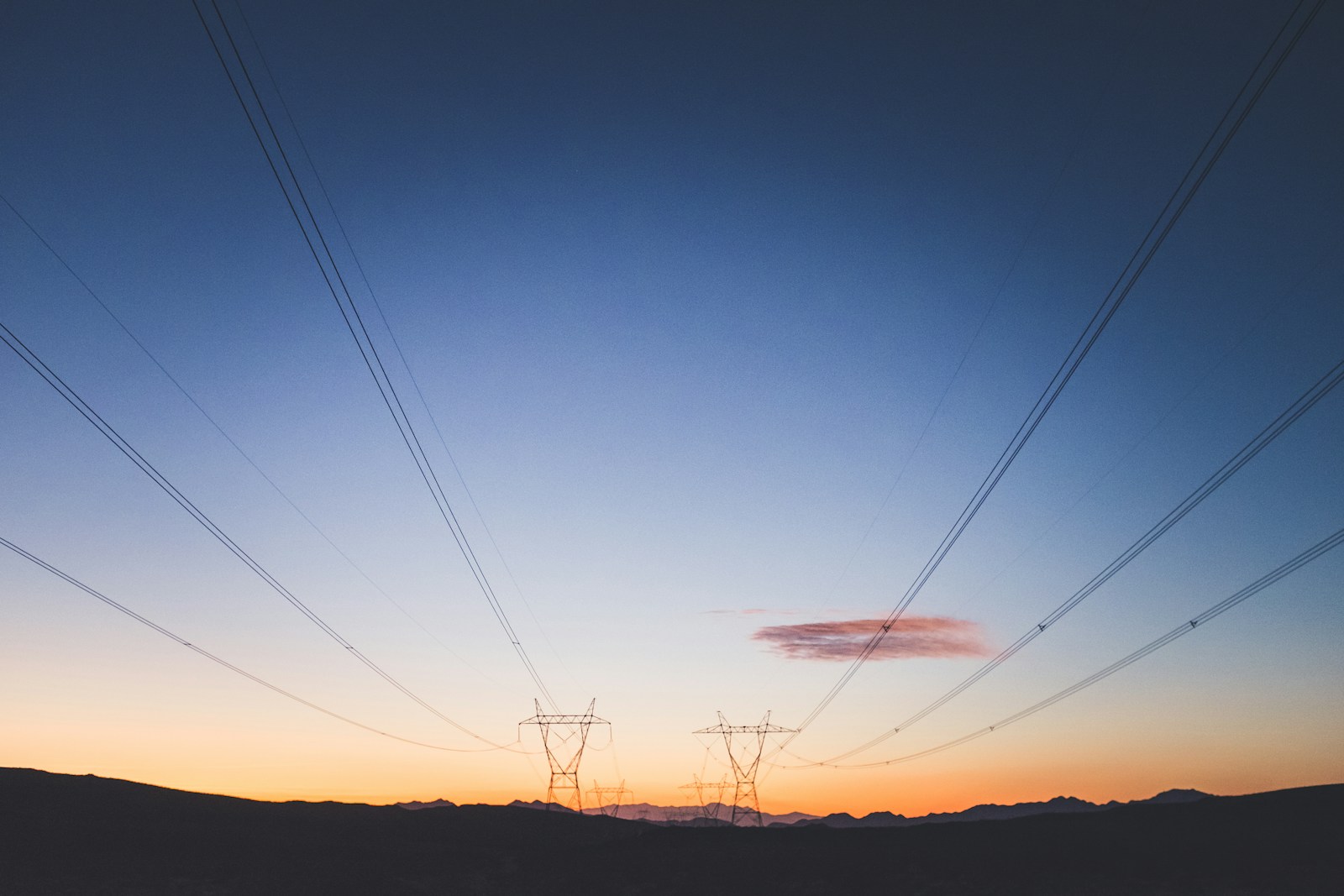 Two electrical transmission towers against a golden sky