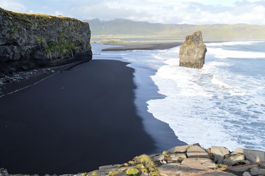 landscape photography of body of water and rock formation in Dyrhólaey Iceland