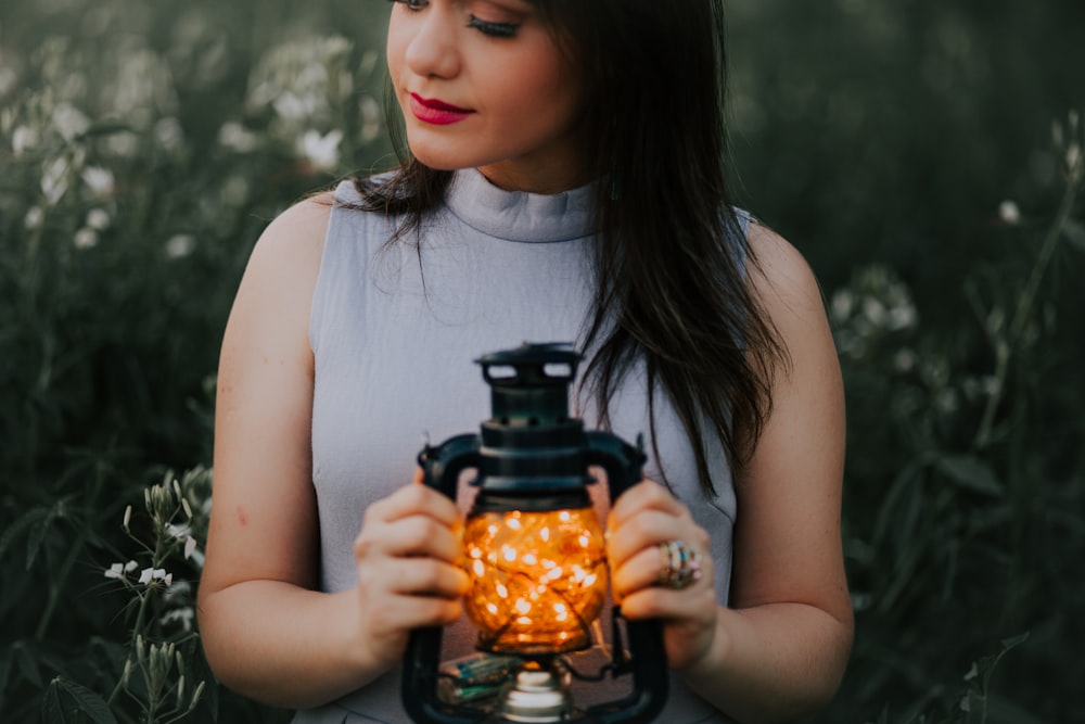 woman in gray turtle neckline top holding black camping lantern