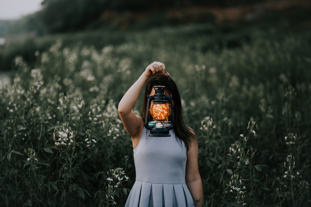 woman in gray dress holding kerosene lamp