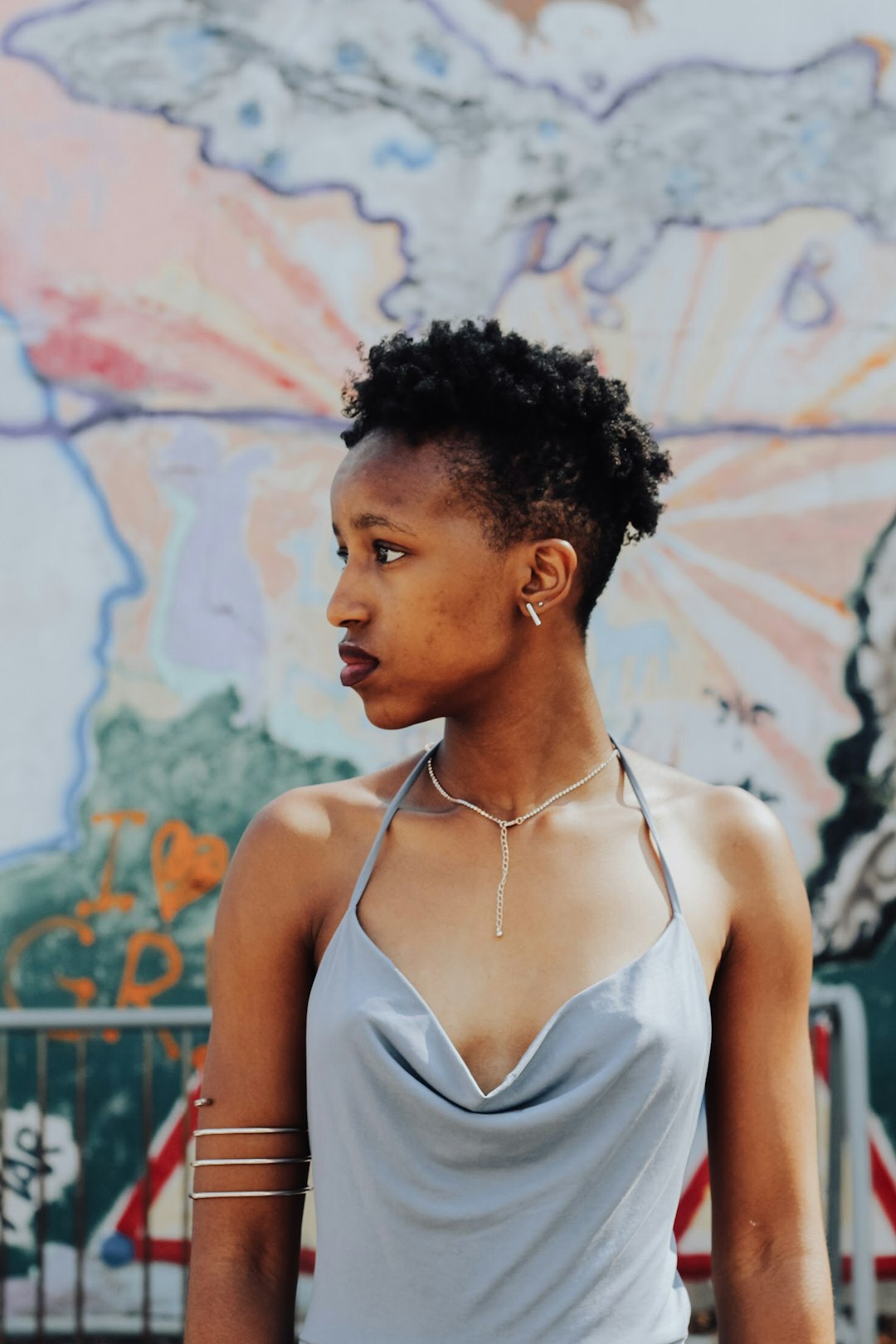 woman in gray halter-top drape-neck tank top standing near wall graffiti