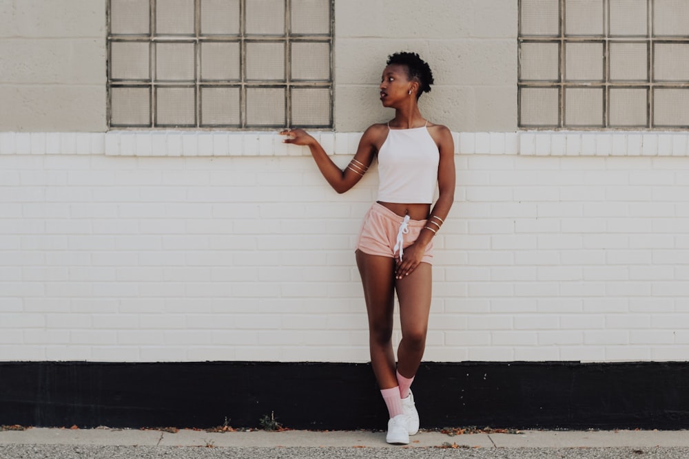 woman wearing white crop top and leaning on wall