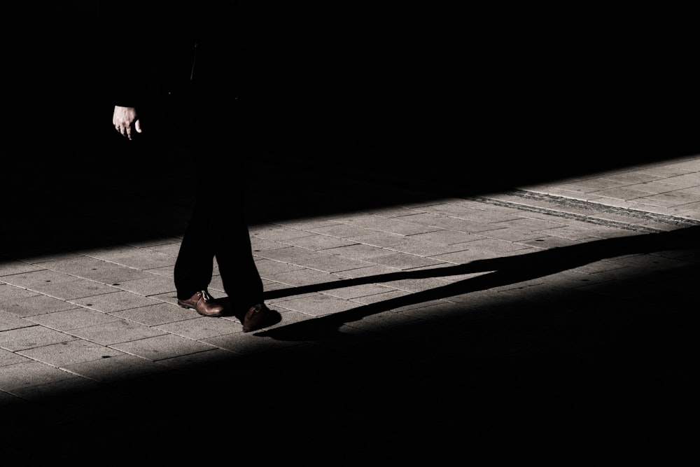 person walking on narrow pathway with shadow on gray floor