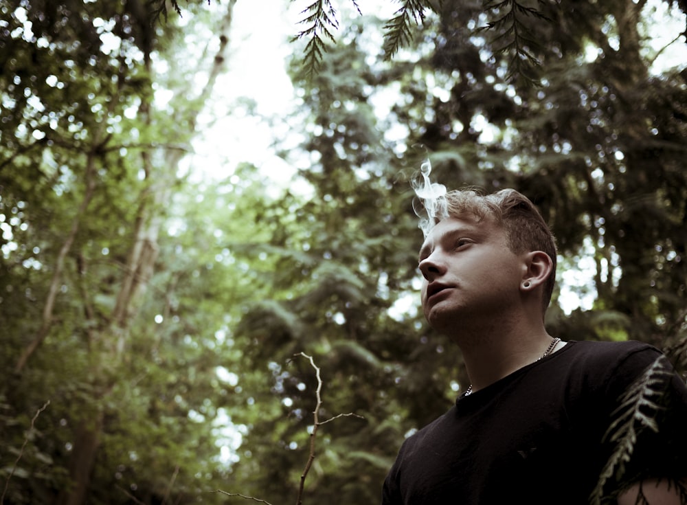 man wearing black shirt and surrounded by trees