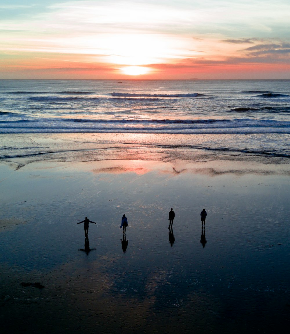 silhouette of four people on body of water under gray clouds during golden hour