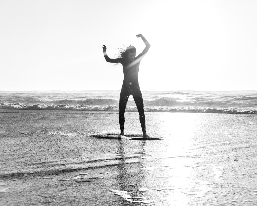 Foto in scala di grigi di una donna che cavalca lo skimboard