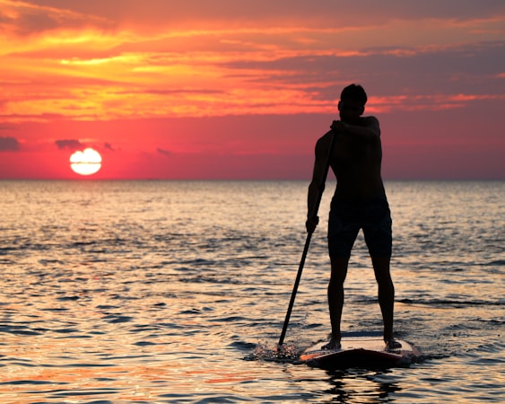 Pemula belajar stand up paddle saat golden hour dengan perlengkapan aman
