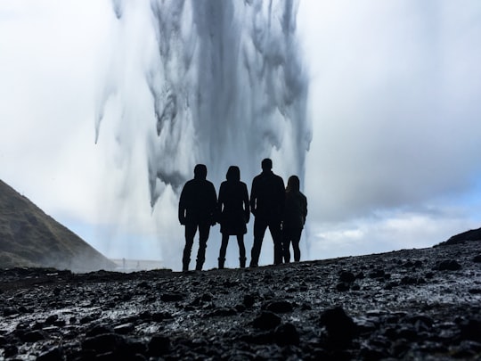 four person's looking at geyser in Seljalandsfoss Iceland