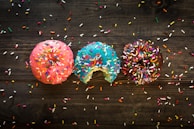 pink, blue, and chocolate with sprinkles doughnuts on table