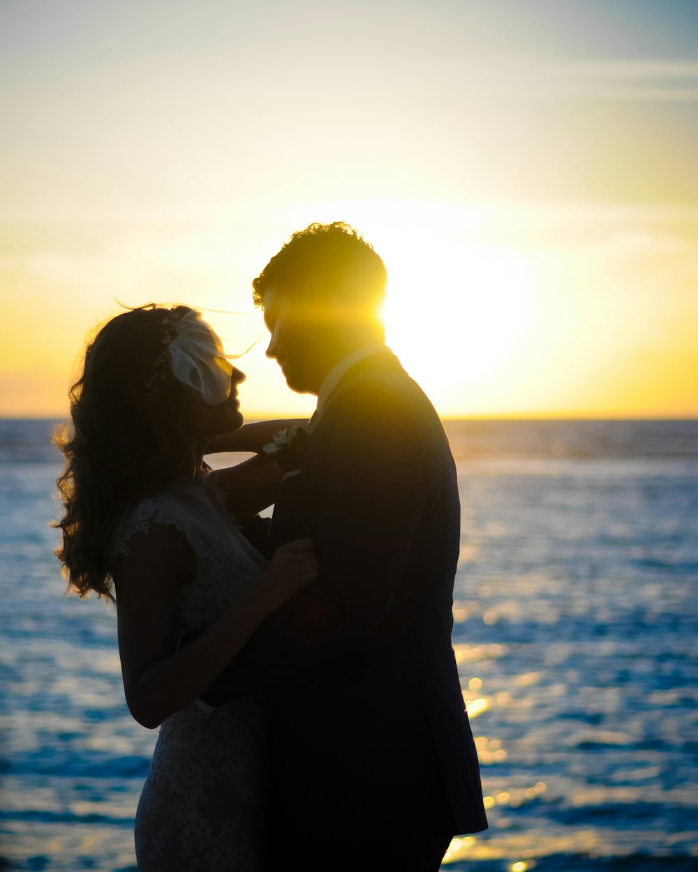 man hugging his wife in front of ocean during daytime