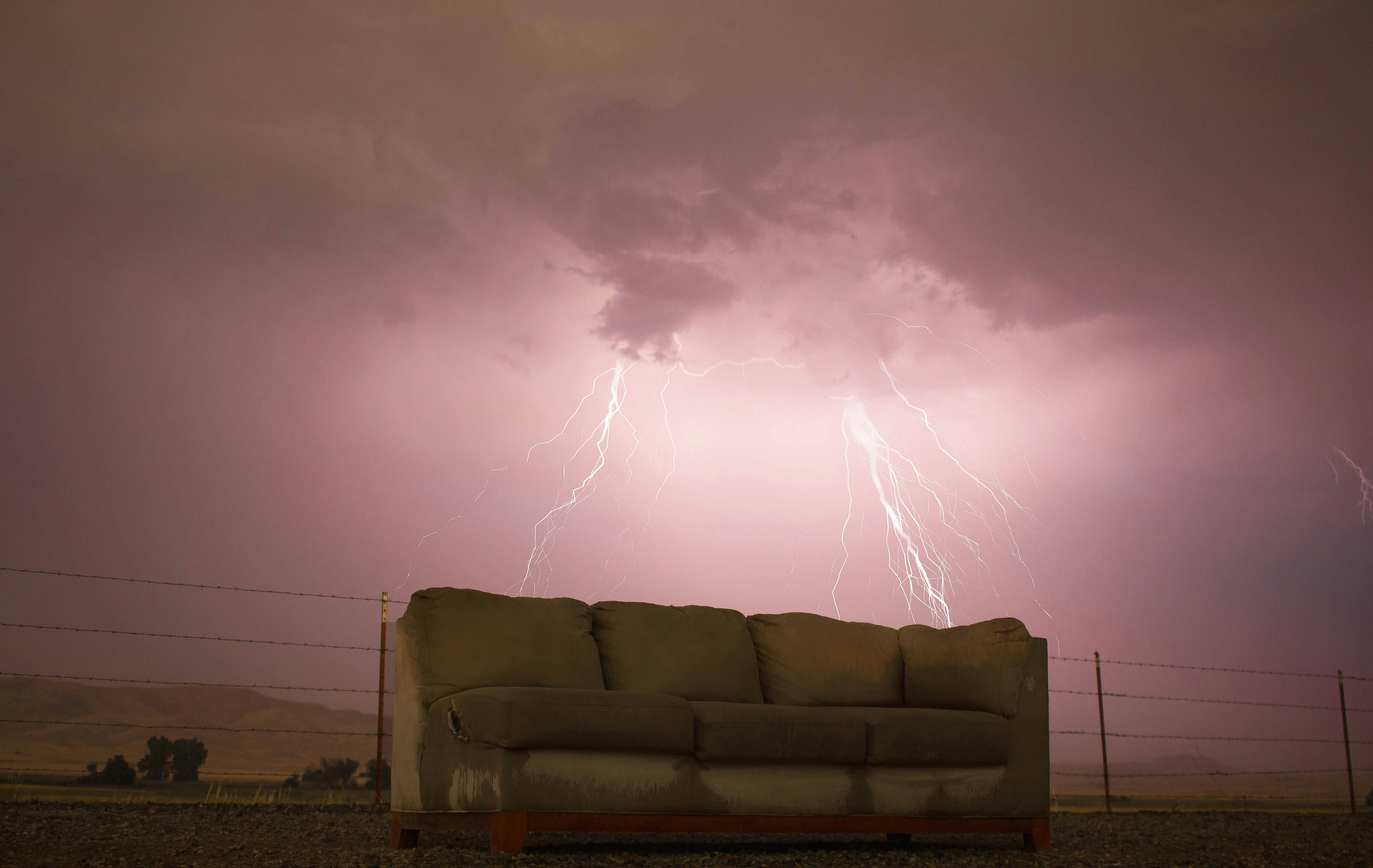 A single coach sits out in what appears to be a lightning storm. The background is a pinkish shade.