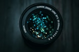 Close-up of a vintage camera lens with reflections of city lights in the glass.