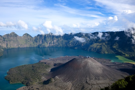 brown and green mountain surrounded by calm water at daytime in Mount Rinjani Indonesia