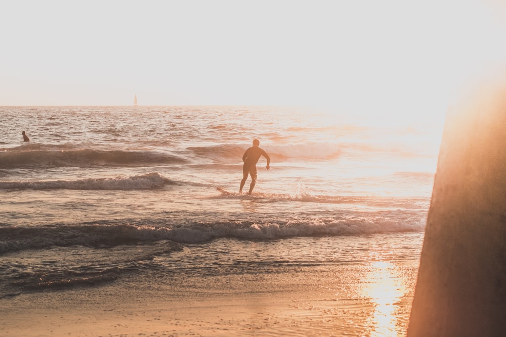 man riding skimboard during golden hour