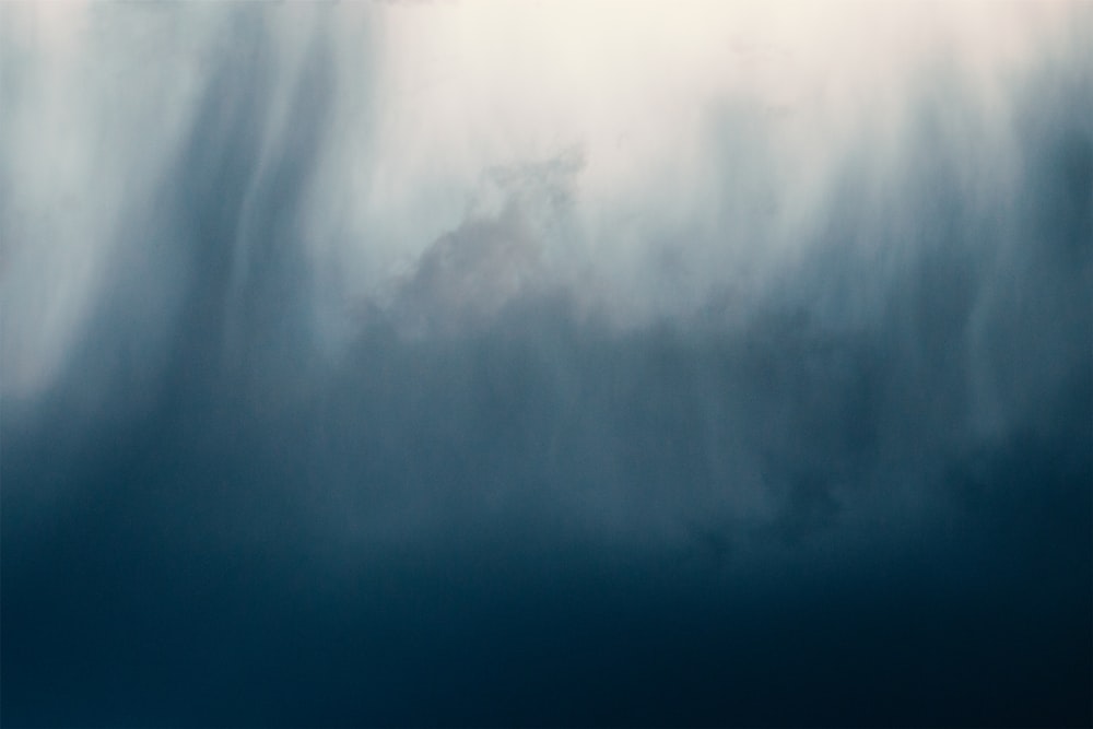 ein Vogel, der durch einen wolkenverhangenen blauen Himmel fliegt