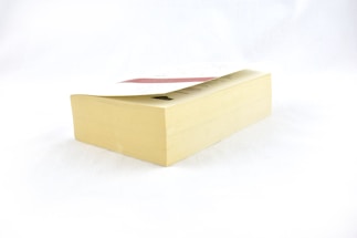 A thick paperback book resting on a flat surface, displaying its side with visible pages. The cover appears partially visible at the top.
