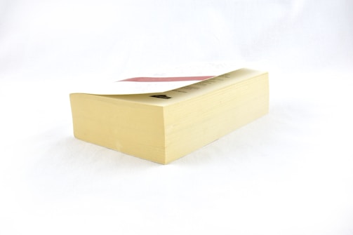 A thick paperback book resting on a flat surface, displaying its side with visible pages. The cover appears partially visible at the top.
