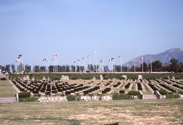A serene memorial garden with flags gently waving under a clear blue sky.
