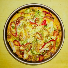 A freshly baked large pizza topped with melted cheese and colorful vegetables.