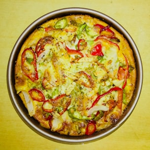 A freshly baked large pizza topped with melted cheese and colorful vegetables.
