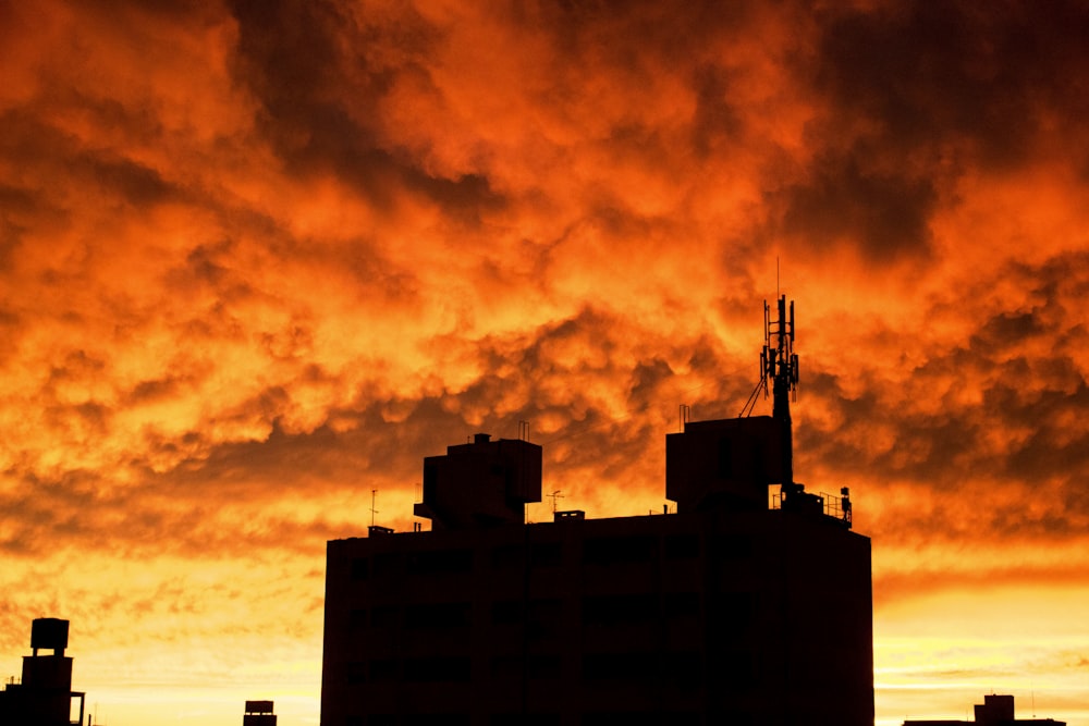 silhouette of building under orange clouds