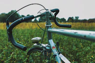 A close-up of a rental bike’s handlebar with the ocean and sky blurred in the background.