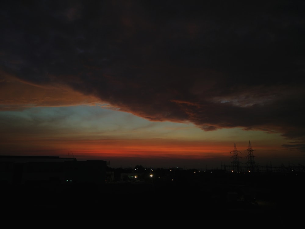 silhouette of power transmission under cloudy sky