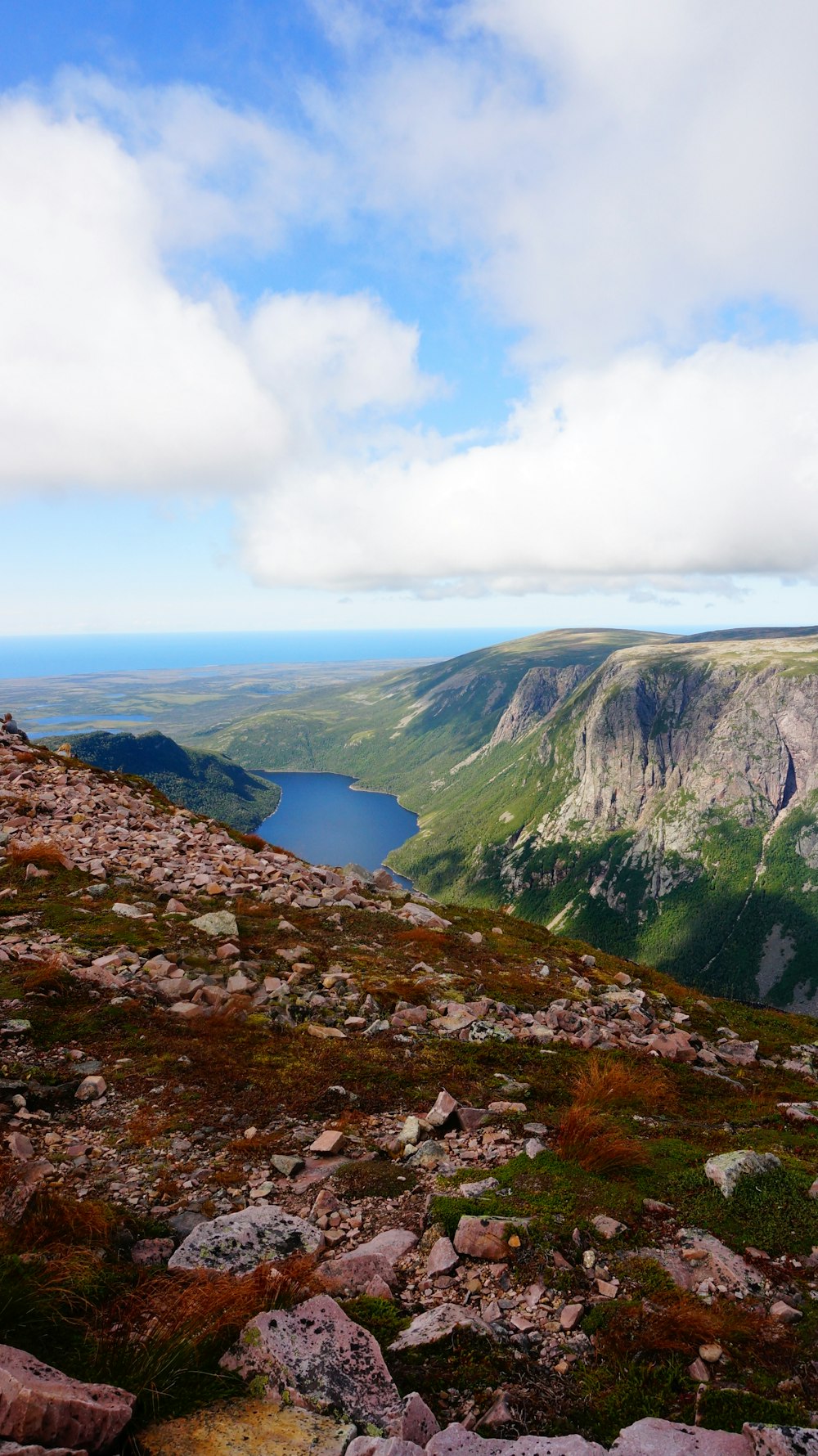 body of water in between of mountains under cloudy sky