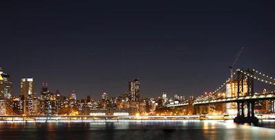 Nighttime view of the New York City skyline glowing with city lights.
