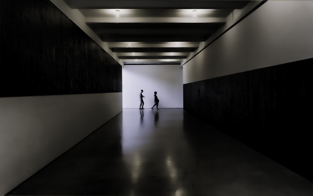 Due persone che camminano verso l'edificio bianco e nero