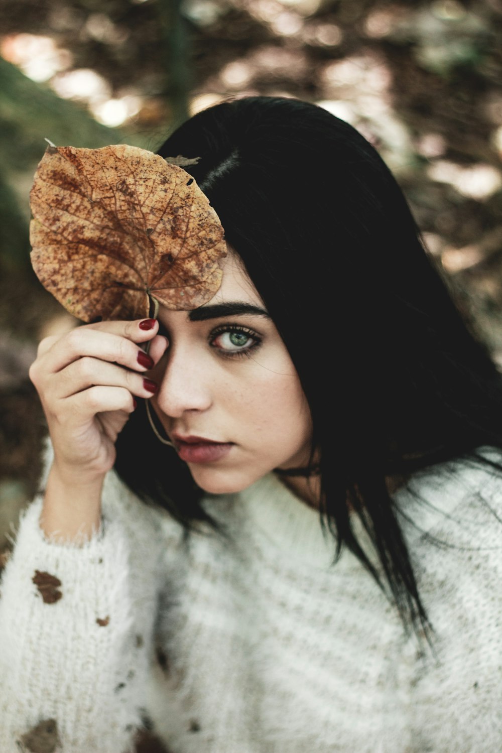 Mujer de fotografía de enfoque superficial sosteniendo hoja seca