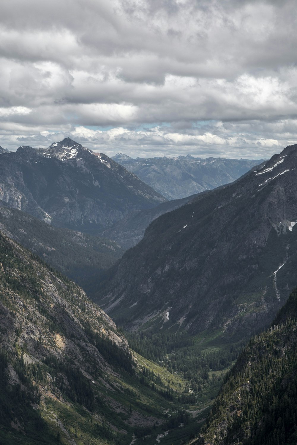 Photographie aérienne de la vallée et de la montagne sous les nuages blancs pendant la journée