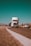 Photo of a smiling truck driver standing beside a big rig under a clear blue sky.