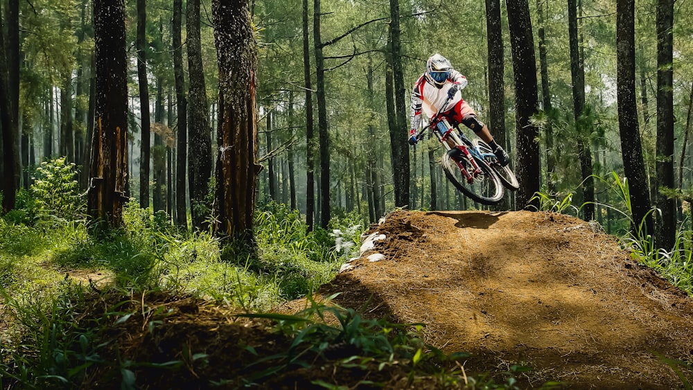 man riding bike doing stunt near green trees during daytime