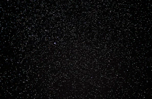 A vast expanse of a night sky filled with countless tiny stars scattered across a deep black background, with a single noticeably brighter star. The scene embodies the vastness of the universe.